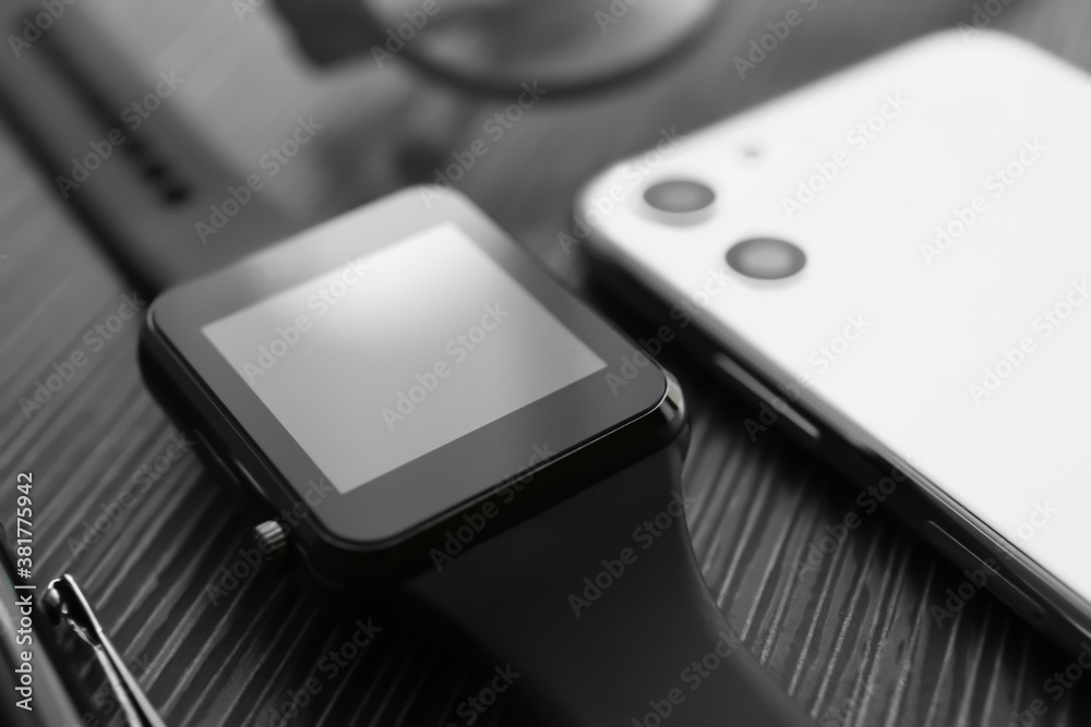 Stylish smart watch and phone on black table, closeup Stylish smart watch and phone on black table, closeup
