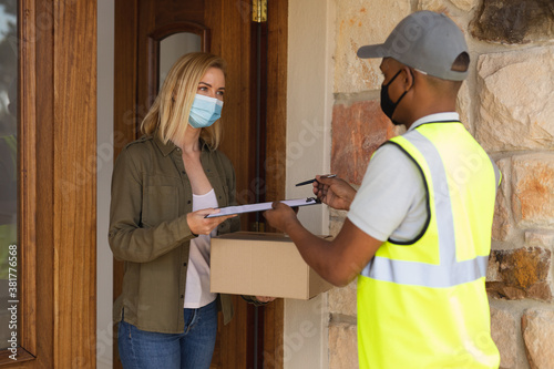 Delivery man delivering package to woman wearing face mask at home photo