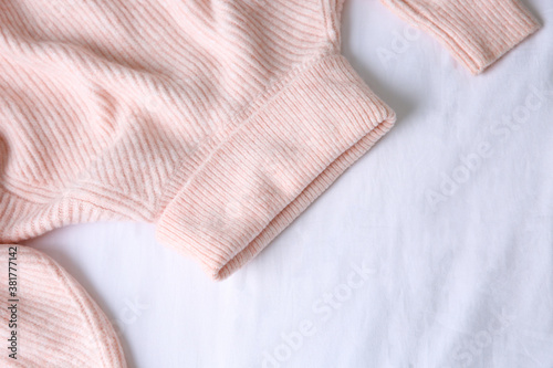 Pink warm sweater on white crumpled fabric, top view