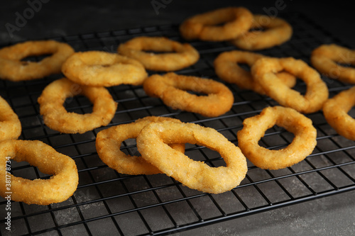 Cooling rack with fried onion rings on grey table