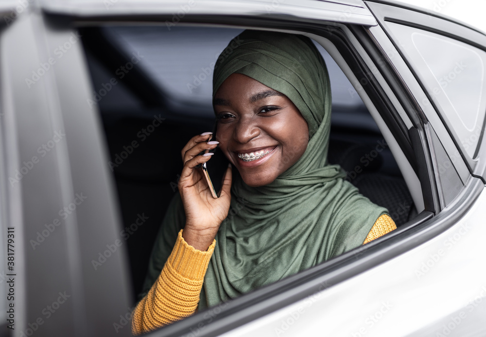 Riding Taxi. Smiling Black Muslim Woman Talking On Cellphone On Car's Backseat Riding Taxi. Smiling Black Muslim Woman Talking On Cellphone On Car's Backseat