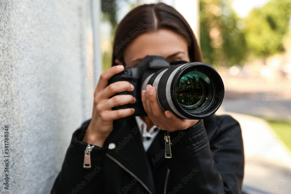 Private detective with camera spying near building on city street