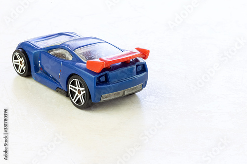 An old and shabby blue children's toy stroller isolated on a white marble background. Miniature car. Used toy.