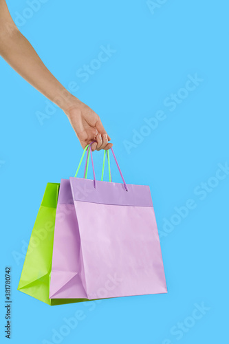 Woman with paper shopping bags on light blue background, closeup