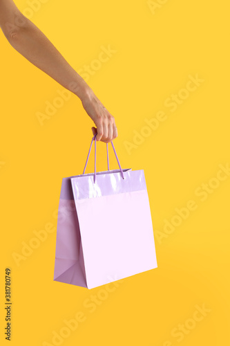 Woman with paper shopping bag on yellow background, closeup