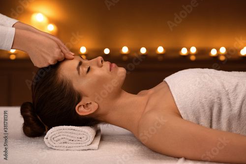 Unrecognizable therapist massaging sleeping woman forehead, side view
