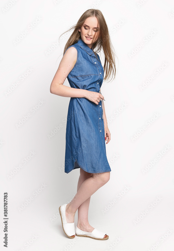 Beautiful cheerful young woman in a blue denim dress on a white background. Concept photo for clothing advertising. Isolate Beautiful cheerful young woman in a blue denim dress on a white background. Concept photo for clothing advertising. Isolate