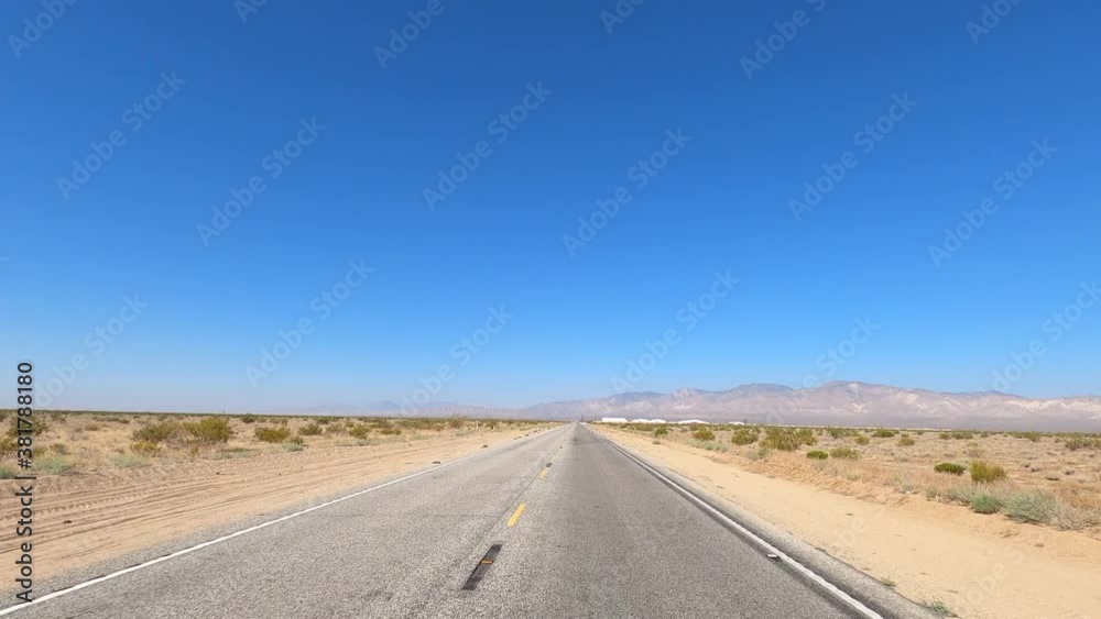 Driving down a straight, empty road through the barren landscape of the Mojave Desert - point of view Driving down a straight, empty road through the barren landscape of the Mojave Desert - point of view
