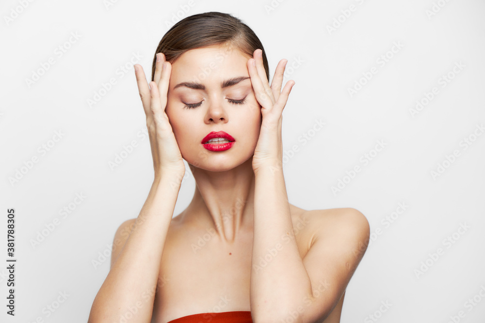 woman with bare shoulders With closed eyes, red lips are holding onto the face body care woman with bare shoulders With closed eyes, red lips are holding onto the face body care