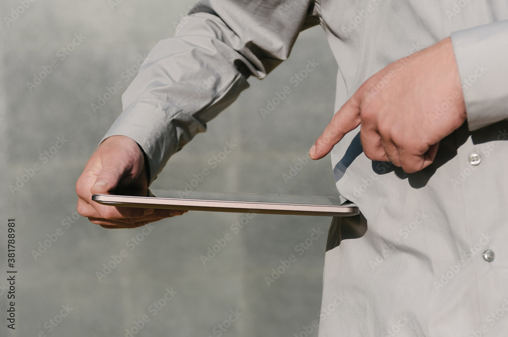 Close-up, Finger in front of tablet screen, in hand, Business man. against the background of a concrete wall.