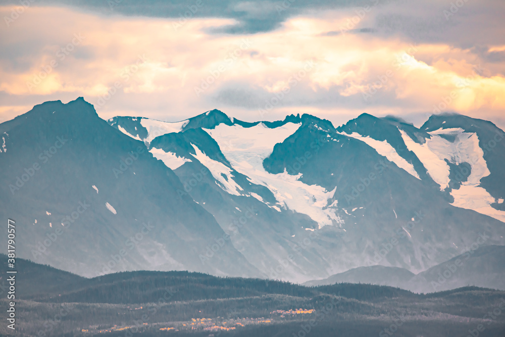Huge snow capped mountains on a hazy sunset afternoon seen in northern British Columbia, Canada taken in fall autumn, September. 