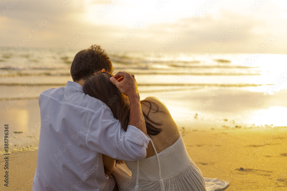 Fototapeta premium Couple in love watching sunset together on the beach travel summer holidays. People romance concept.
