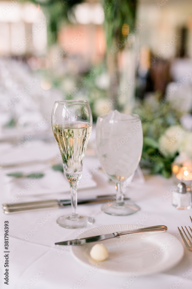 A champagne glass and a water glass at a wedding reception of an elegantly decorated table. 