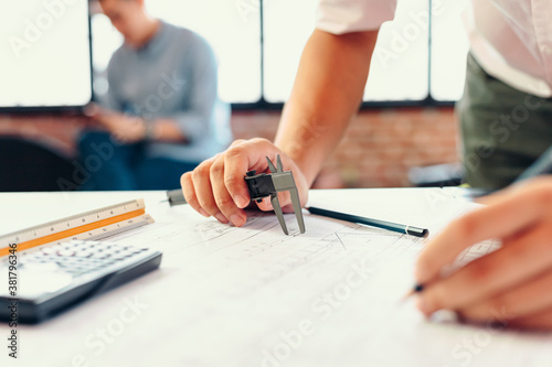 Valokuva Engineering hands hold vernier caliper working and checking drawing blue print scale on workplace