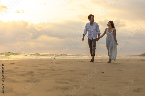 Young couple holding hands and walking on the beach.