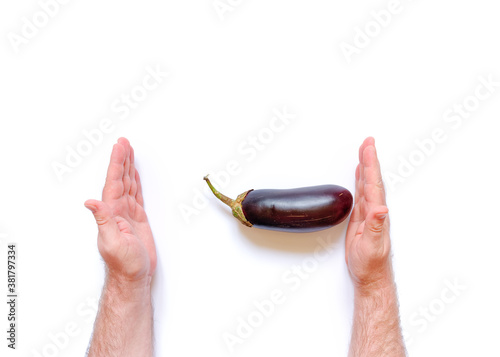 Man's hand holds fresh ripe eggplant on a white background. Harvesting concept. An allegory on the size of male sex ogans. Size comparison. Images for the male doctor's office. photo