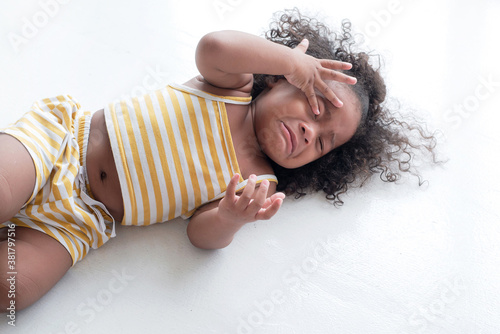 Dark skinned child crying and shouting with tantrum laying on the floor at home