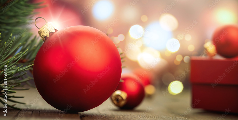Red balls on rustic wooden table on blurred Christmas lights in the background Red balls on rustic wooden table on blurred Christmas lights in the background