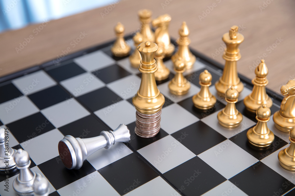 The silver queen pawn on the chess board kneels to the golden queen pawn standing on the coin