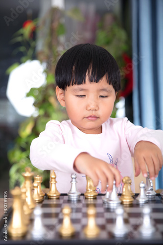 Cute Chinese little girl learning to play chess