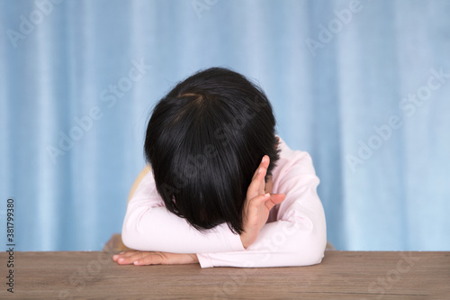 фотографія Little girl lying on the table in front of the blue curtain background pretendin