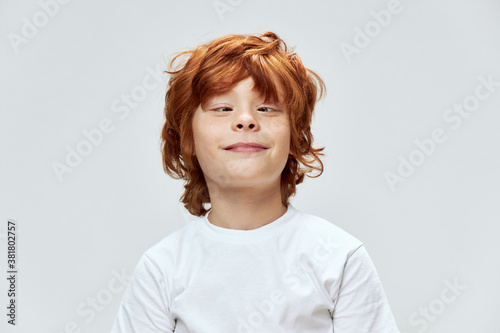 Grimacing red-haired boy squinting eyes cropped view and white t-shirt 