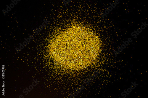 Sparkling golden glittering circle shape isolated on black background.