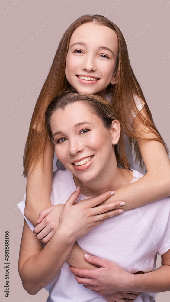 Elder mother and teenager daughter hug. Happy family portrait. Similar smile. Next generation love. Single mom. Mature parent. Smiling people group. Attractive posing together. Two hand connection Elder mother and teenager daughter hug. Happy family portrait. Similar smile. Next generation love. Single mom. Mature parent. Smiling people group. Attractive posing together. Two hand connection