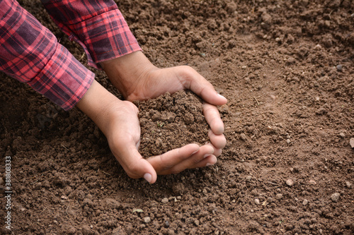 Hands holding soil in agricultural field