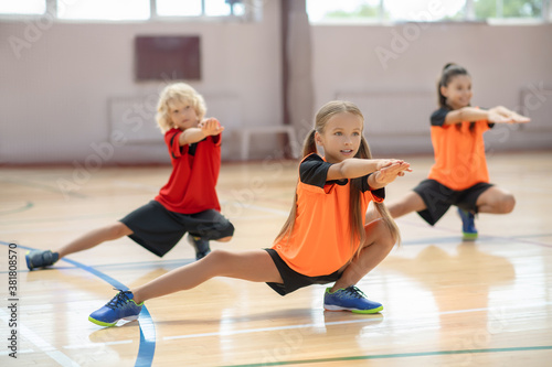 Three kids exercising in the gym and looking concentrated