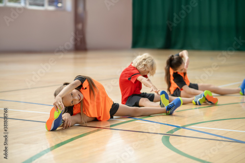 Three kids sitting on the floor and stretching photo