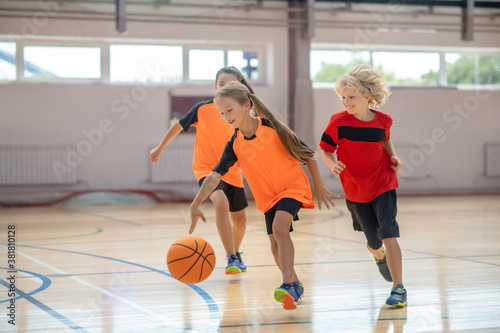 Children in bright sportswear playing basketball and looking excited