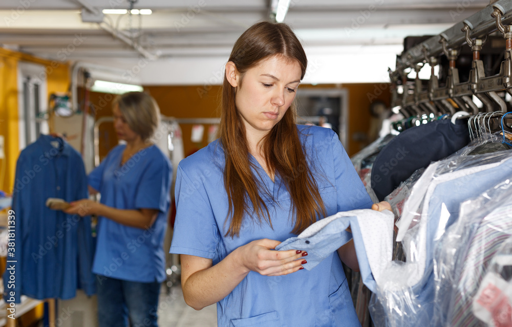 Obraz premium Two female dry-cleaning salon employees in process of work