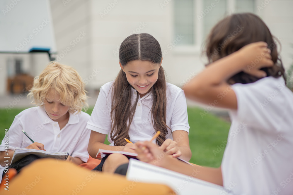 Children in white shirts sitting and studying together Children in white shirts sitting and studying together