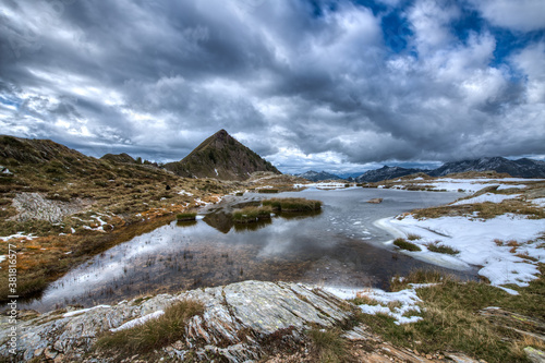 Small alpine lake with the first snow on the Italian alps