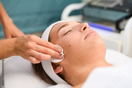 Cleansing face with cotton pad at salon