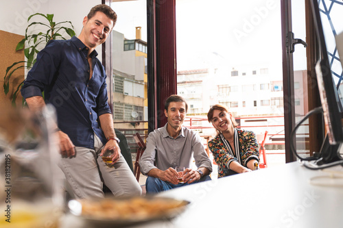 Three young architects discussing about business issues after the meeting inside the conference room in a fancy elegant office in Lisbon. Three business persons talking informally and drinking a beer