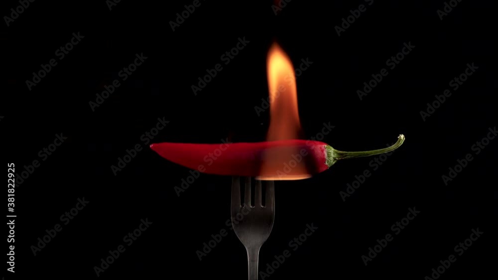 Hot red chili pepper on a fork in flames on a black background. Spicy food concept. 4K Hot red chili pepper on a fork in flames on a black background. Spicy food concept. 4K