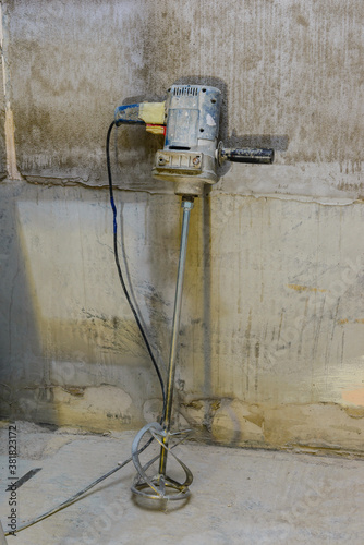 Repairs in the bathroom. Mixer for building materials on a background of gray concrete walls.