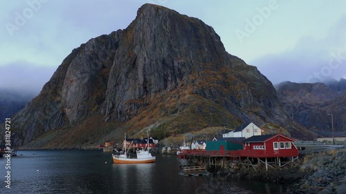 Harbor fishing boat of Hamnoy village in morning with Olstinden and Lilandstinden mountains in background, Lofoten, Norway