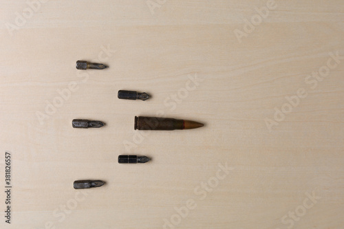 Military rifle bullet and screwdriver attachments on wooden background. Abstract concept of hard workers protest power photo