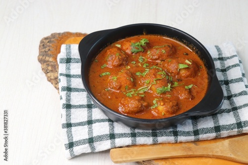 Indian cuisine - Kashmiri Dum Aloo or Potatoes in red gravy over white background. Garnished with coriander. Serve hot with rice or Naan/roti. Copy space. Panjabi Dam alu curry.