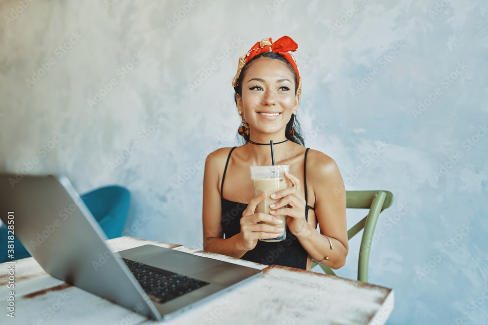 a young mixed race woman drink iced coffee and using her laptop in cafe