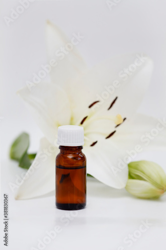 Lily (Lilium candidum) essential oil bottle on Lilium fresh flower background, isolated white