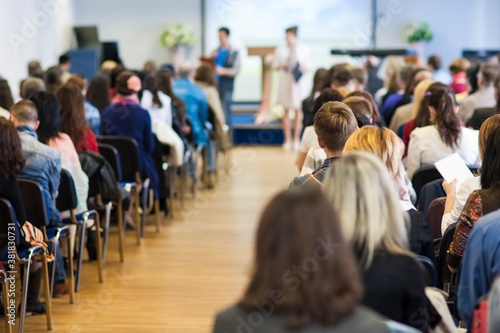 Male and Female Hosts Speaking In Front of the Large Audience At the Conference.