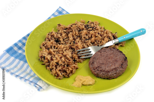 Steak haché de boeuf avec du riz pilaf et de la moutarde servis dans une assiette sur fond blanc photo