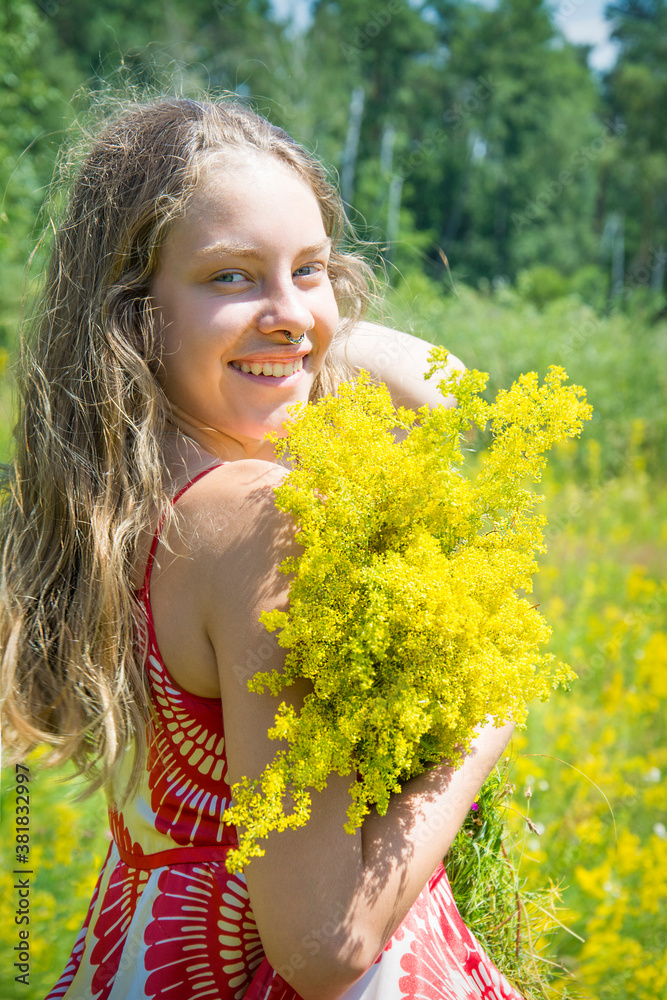 In summer, on a bright sunny day, a girl stands in a bright red dress on a blooming field. In summer, on a bright sunny day, a girl stands in a bright red dress on a blooming field.