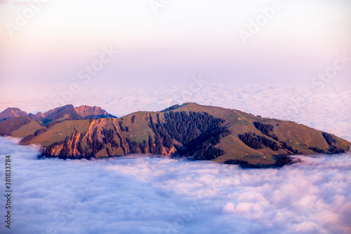 Colorful sunrise on the green hills of Appenzell in Switerland as they emerge from the clouds and fog in an autumn morning