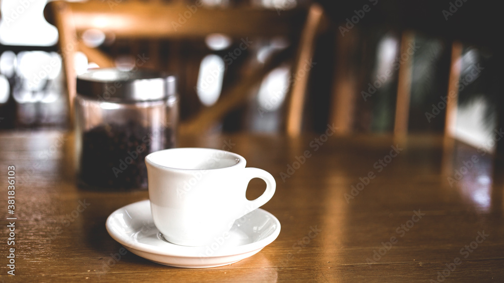 A white coffee cup on a brown wooden table. A white coffee cup on a brown wooden table.