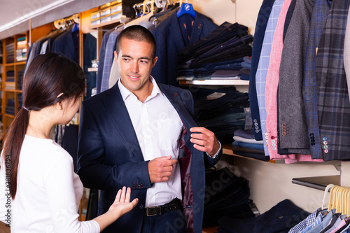 Smiling couple examining various suits in mens cloths store. High quality photo © JackF